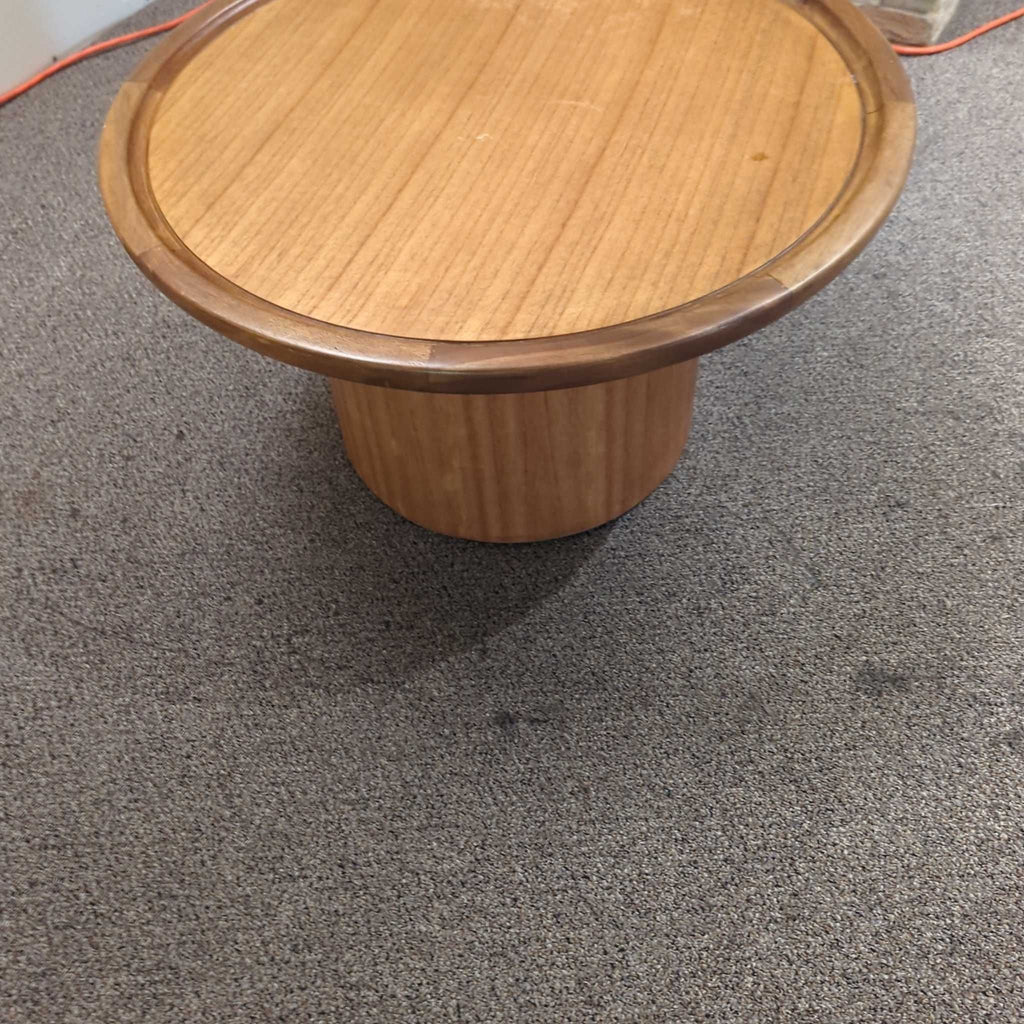 Round wooden Safavieh coffee table with drum base, shown on a carpeted floor.  