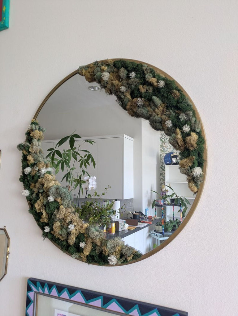 Round mirror framed with lush green moss, blending natural texture with modern décor style.