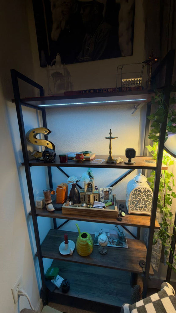 1. Modern metal and wood bookshelf with five shelves, decorated with various trinkets, lights, and greenery in a cozy room.