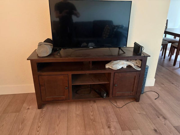 1. Living Spaces dark wood entertainment center with TV, game console, and open shelves in a home setting.