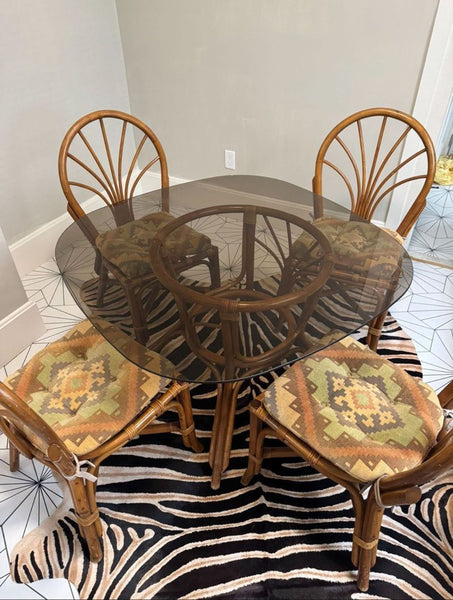 1. Reperch Dining Set with rattan chairs and patterned cushions around an oval glass table, on a zebra rug.