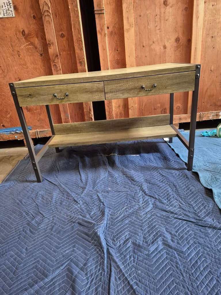 3. Modern industrial-style desk featuring a wood top, two drawers, and a shelf underneath, against a wooden wall.