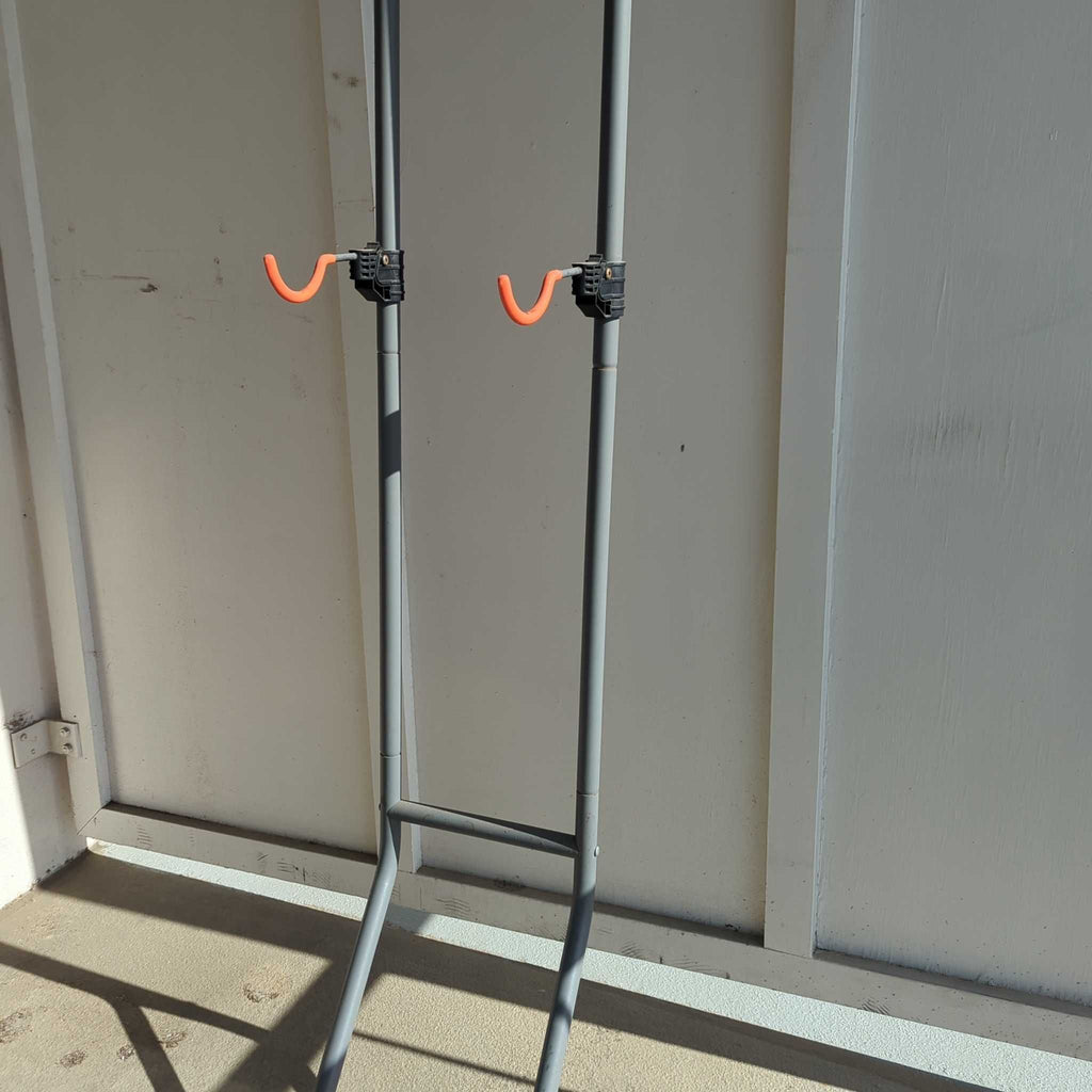Freestanding metal rack with orange hooks, suitable for organizing or storing outdoor equipment.