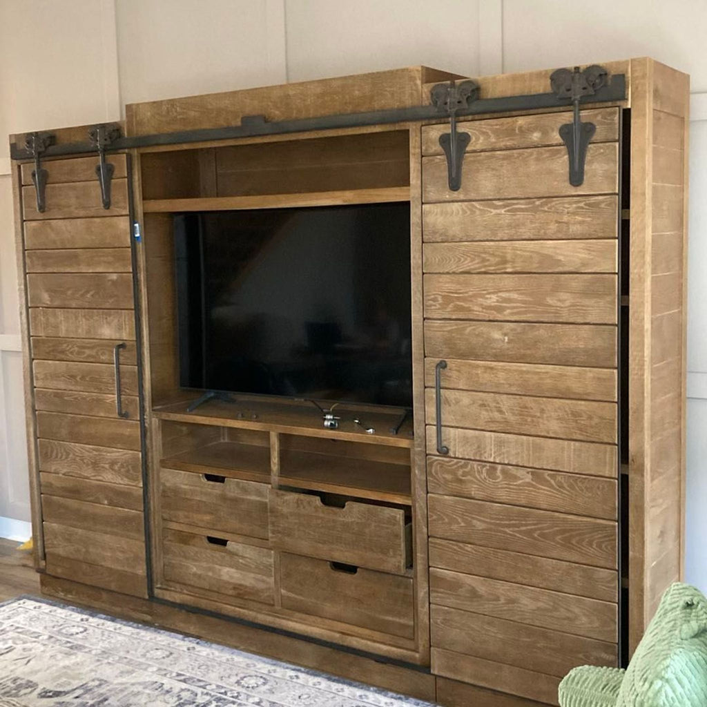 3. Large rustic Arhaus entertainment unit with TV niche, storage drawers, and sliding wood paneled doors.