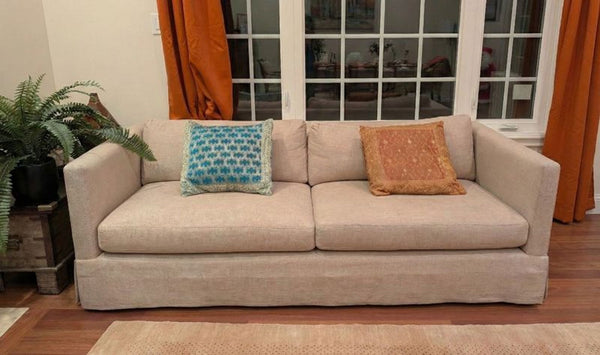 1. Crate and Barrel loveseat with beige upholstery and two colorful throw pillows, placed in a cozy living room.