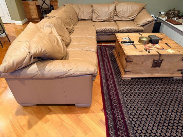 1. Tan leather sectional sofa with plush cushions arranged in an L-shape, placed in a cozy living space.