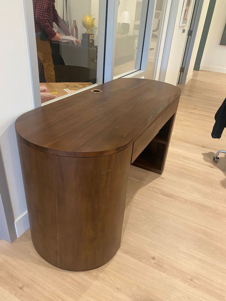 1. Modern wooden desk with rounded edges, integrated shelf, and cable grommet, seen in an office setting.  