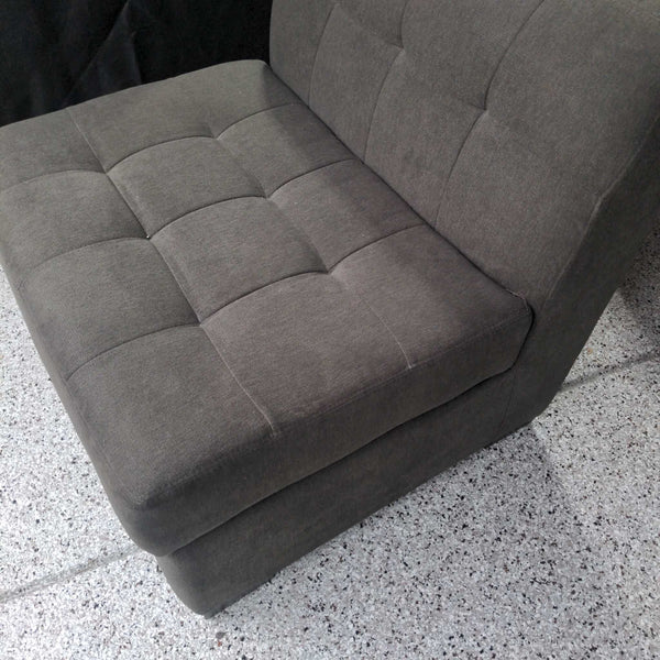 1. Close-up side view of a gray, armless Jonathan Louis lounge chair with tufted seat and backrest.