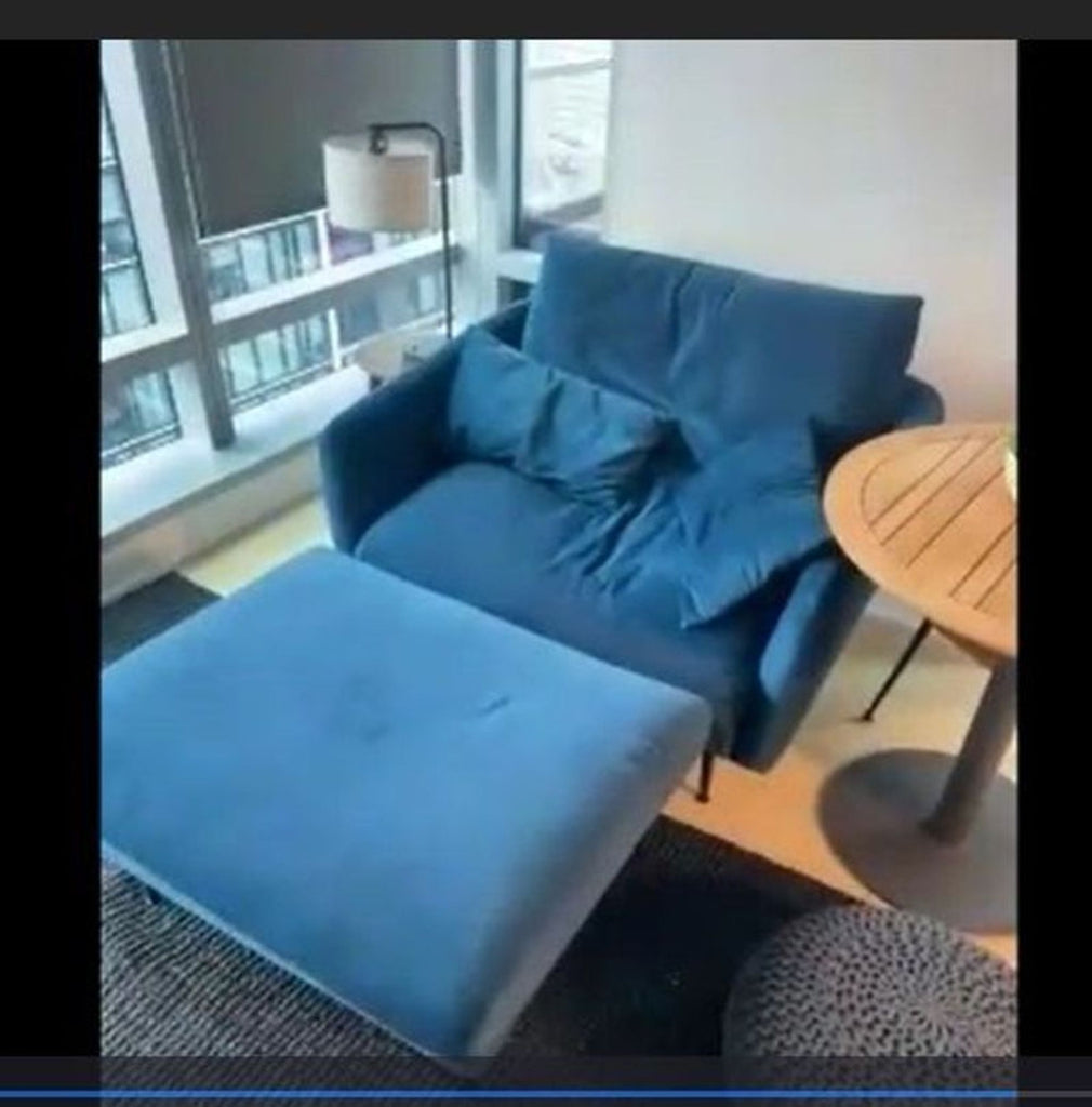 1. Modern blue lounge chair with matching ottoman, placed by a window and round table in a living room.  