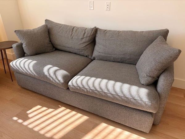1. Gray Crate and Barrel 3-seat sofa with plush cushions, shown in natural light on a wooden floor.