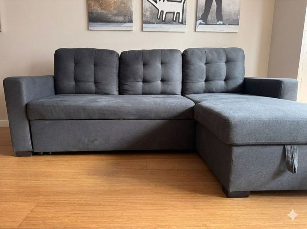 1. Dark gray Ana Furniture sectional sofa with tufted cushions, chaise, and armrests on a wood floor in a living room.