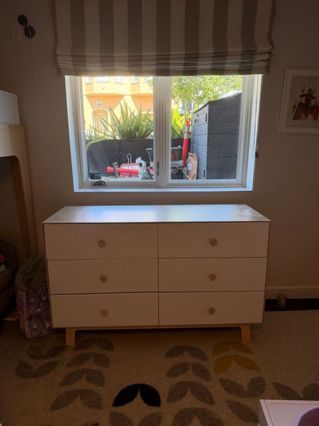1. Oeuf dresser with six white drawers and natural wood knobs placed under a window in a cozy room.  