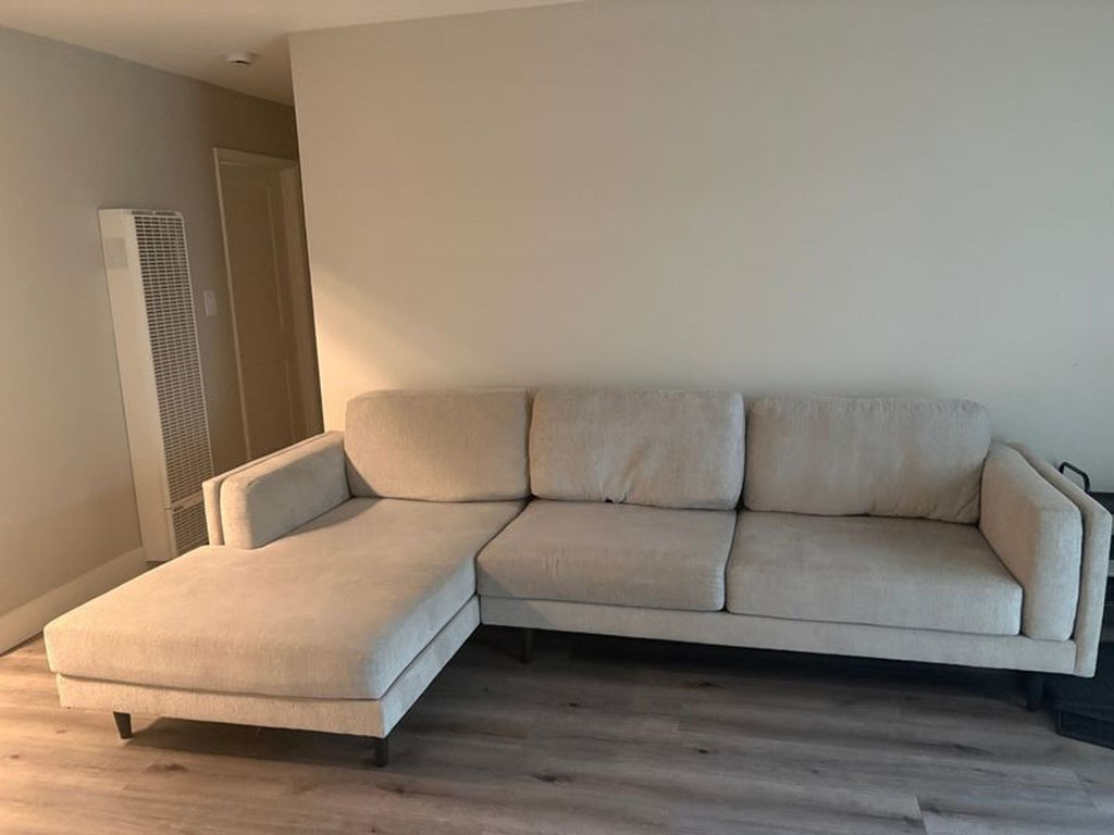1. Modern Living Spaces sectional sofa with L-shape, upholstered in light grey fabric, in a spacious living room.