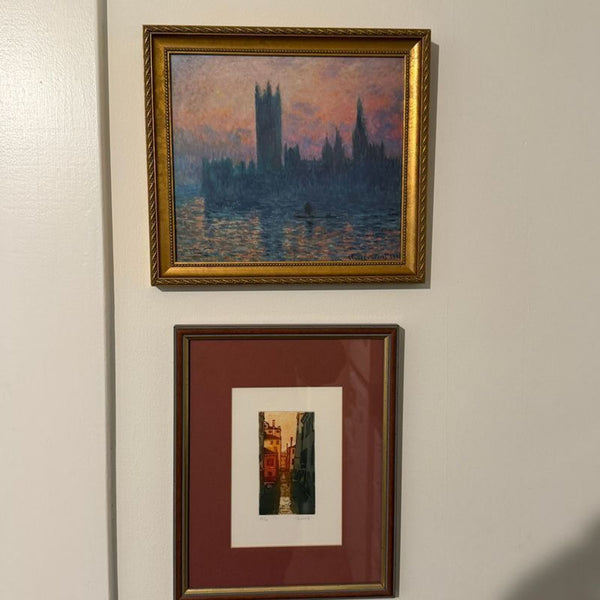 1. Framed prints of cityscapes: one impressionist painting of buildings over water at sunset, and a narrow street scene.