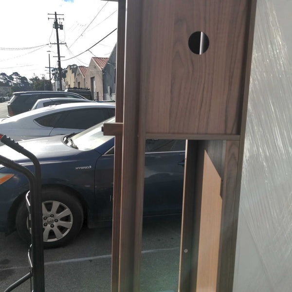 1. Close-up of the back of a wood entertainment center showing cable management holes and outdoor background.  