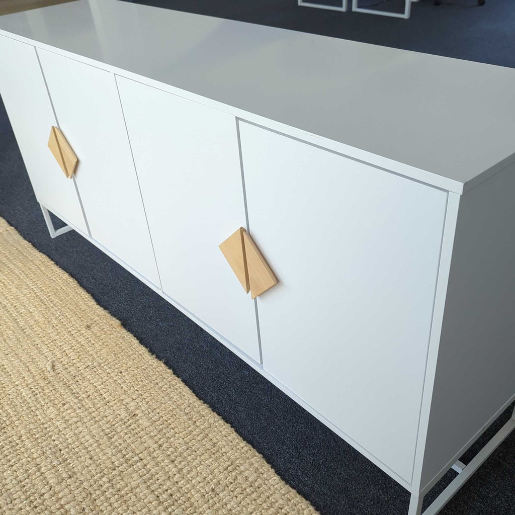 Sleek white credenza featuring minimalist geometric wood handles, placed beside a woven beige rug.