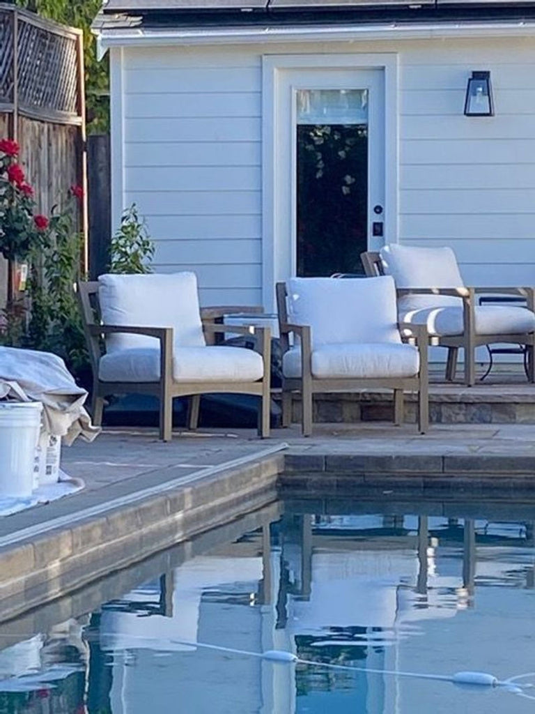 1. Outdoor Pottery Barn bench with a cushioned seat, pictured by a poolside patio alongside matching chairs.