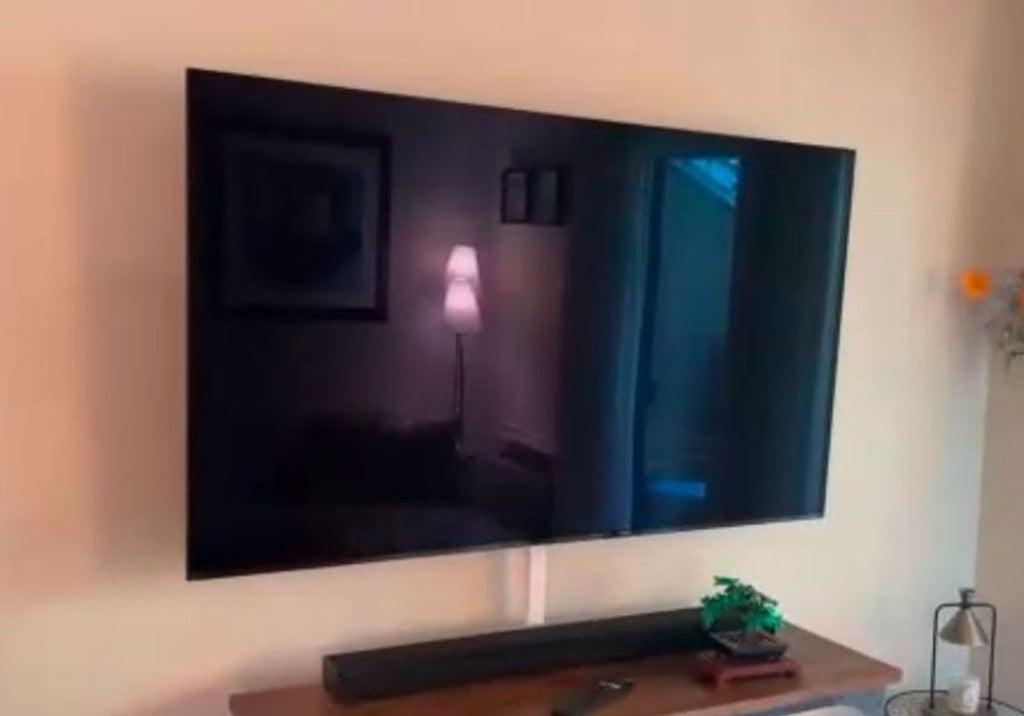 1. Sony TV mounted on a wall above a console with a soundbar and decor, screen turned off.