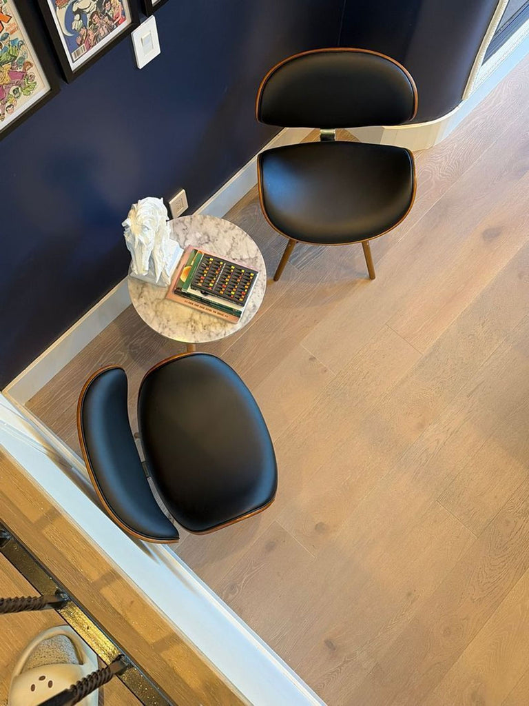 1. Pair of Armen Living dining chairs with curved black seats and wood accents, arranged beside a small marble table.  