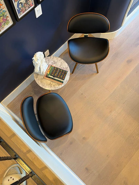 1. Pair of Armen Living dining chairs with curved black seats and wood accents, arranged beside a small marble table.  
