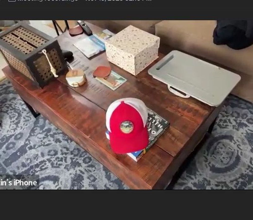 1. Wooden coffee table with a dark finish, holding various items including a red cap, books, and decor on a patterned rug.