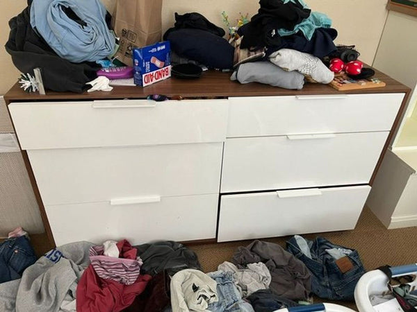 1. Ikea dresser with six white drawers, cluttered with clothes on top and scattered on the floor.