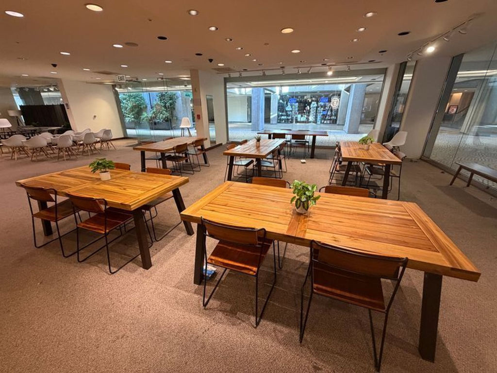 1. Modern dining area with multiple wooden tables and chairs, decorated with small plants, showcased in a showroom.