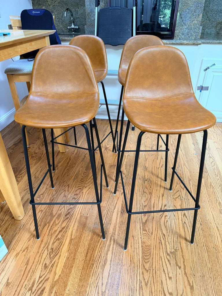 Set of four matching bar stools with curved seats and slim black legs arranged in a row.
