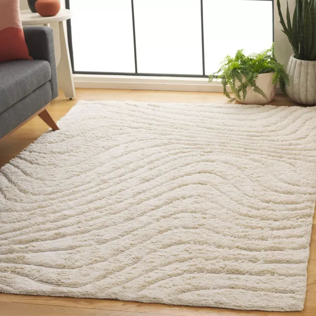 2. Reperch cream rug with textured waves shown in a cozy living room setting near a window and plants.