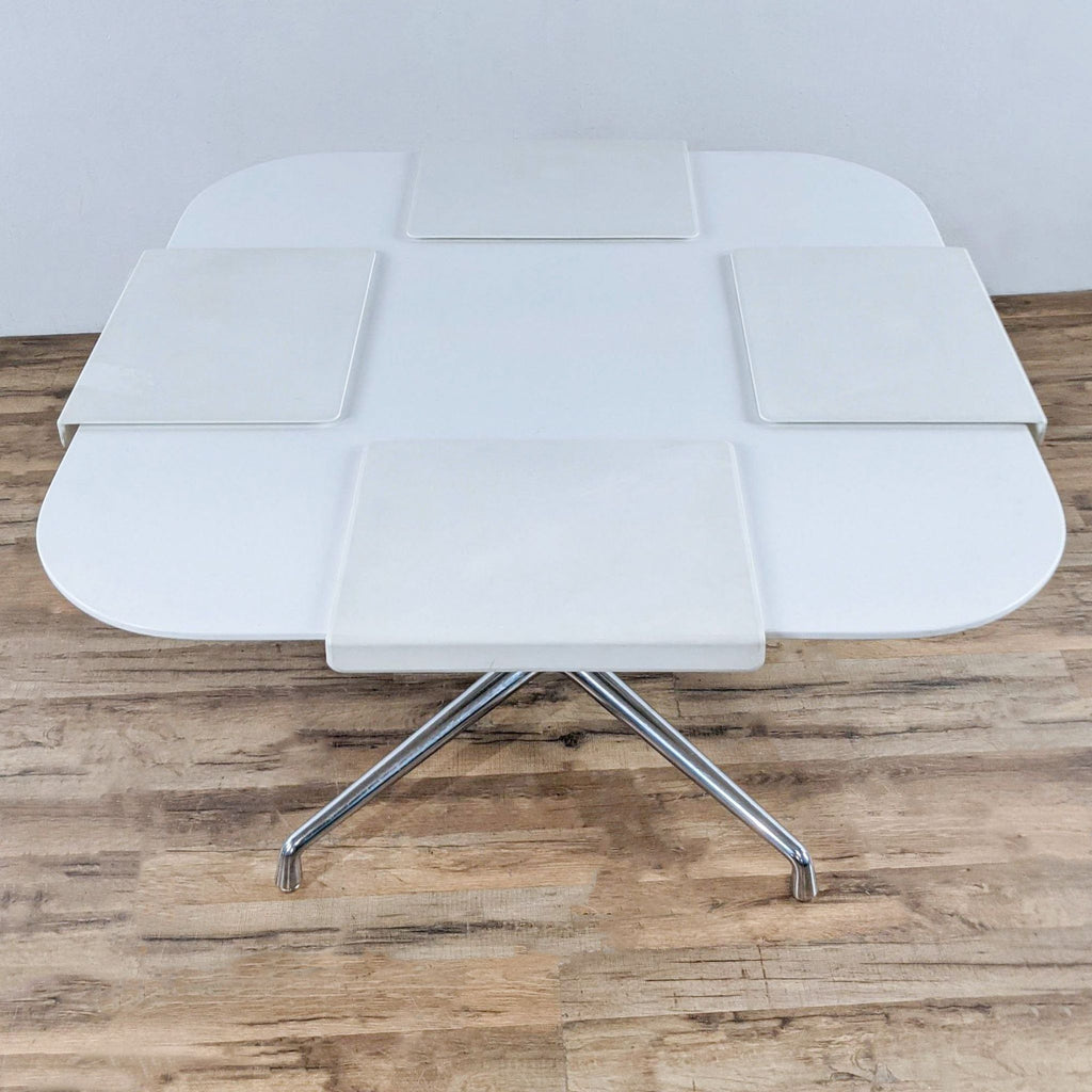 White conference table with four leaves and polished chrome base.