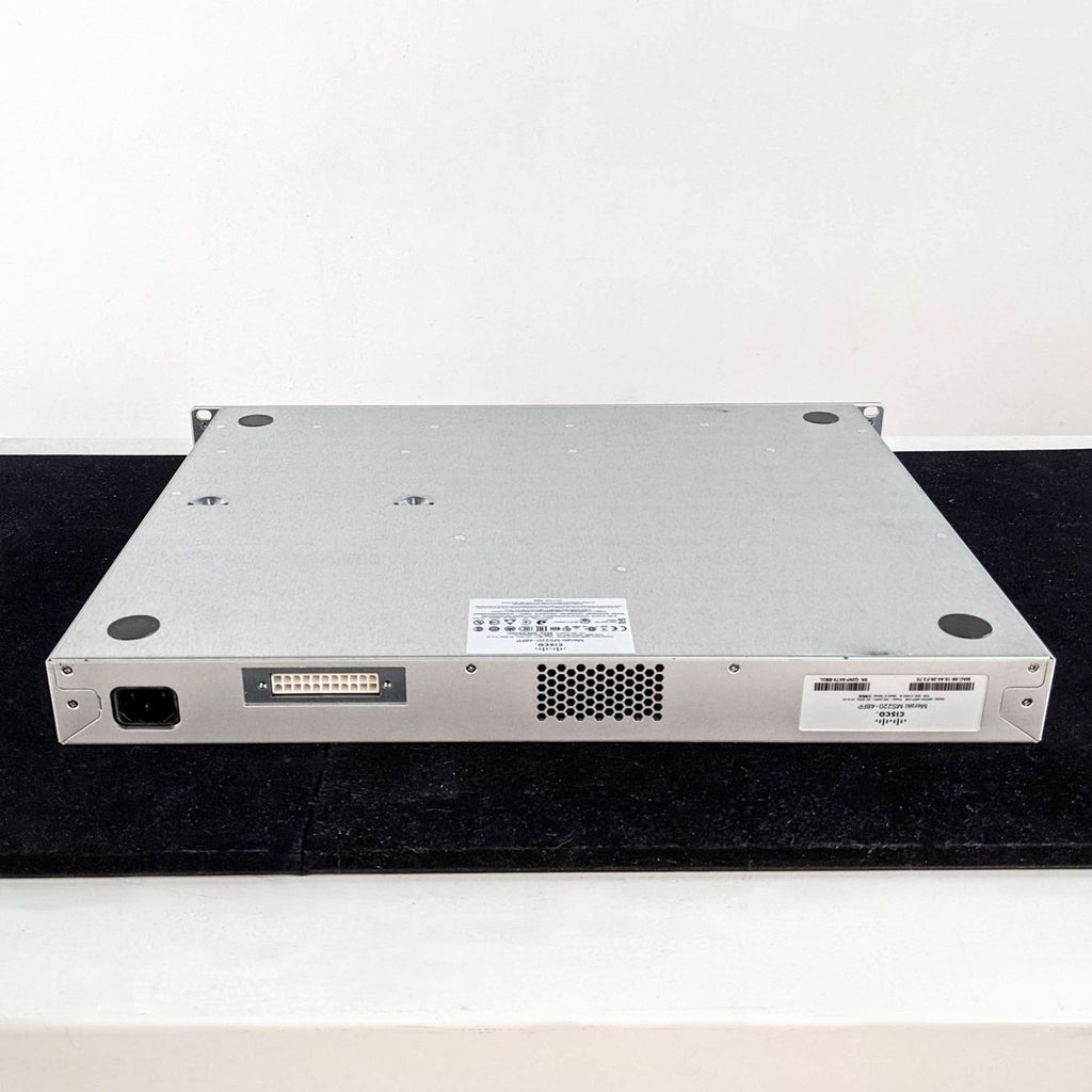 1. Rear view of a Cisco & Bros. network device, showing power input, ports, and vent on a black surface.