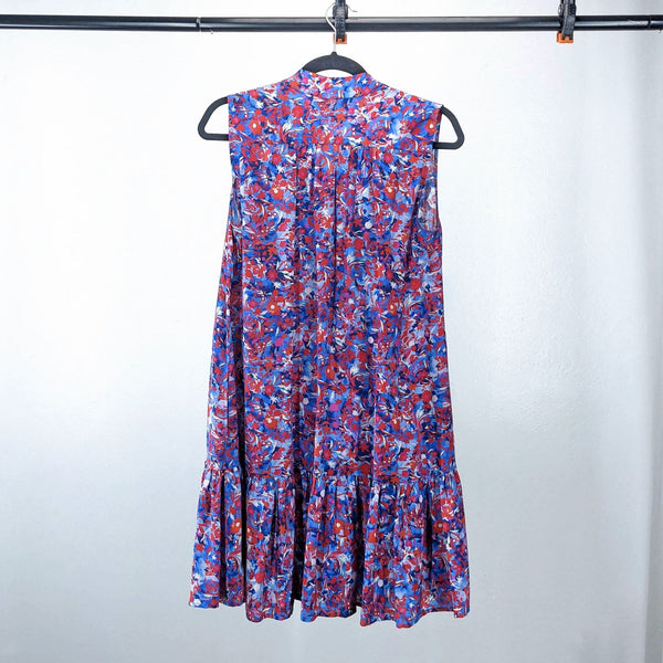 Floral sleeveless dress with vibrant red and blue patterns, hung on a black hanger.