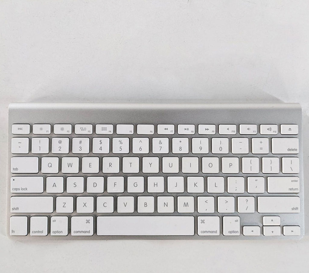 Apple wireless keyboard with white keys and aluminum finish on a white background.