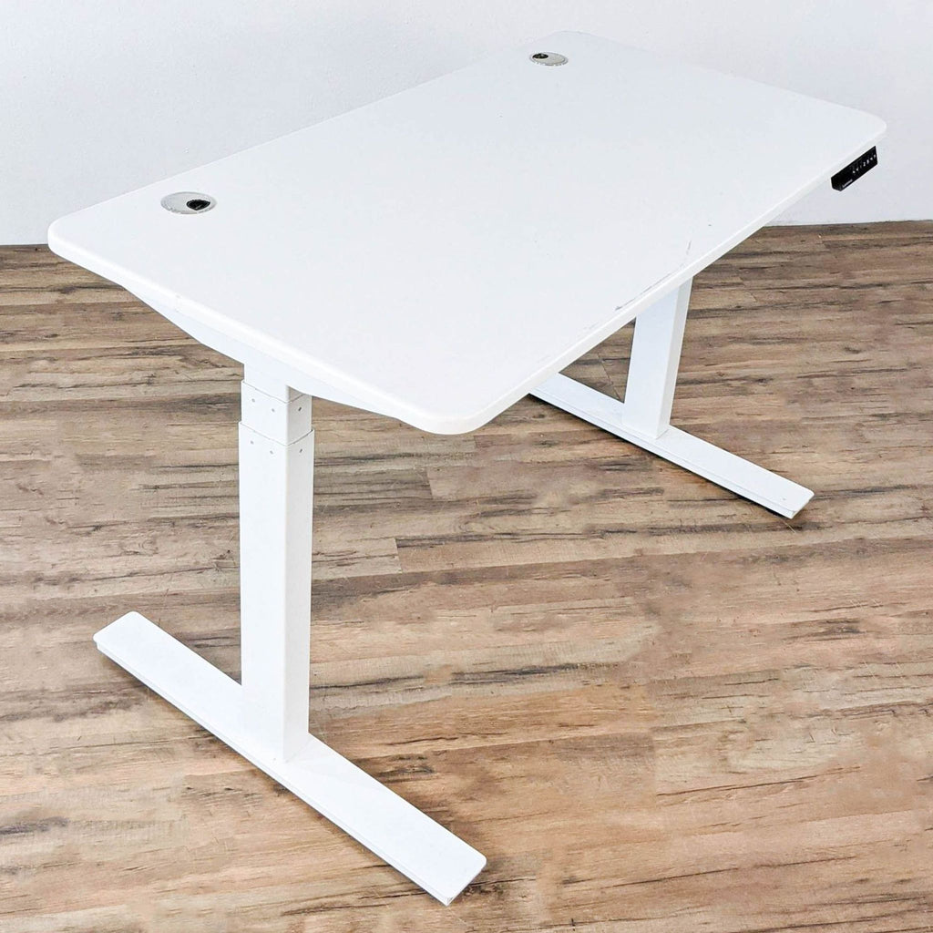 Sit/stand white desk with solid steel frame by Autonomous, shown in a home office setting.