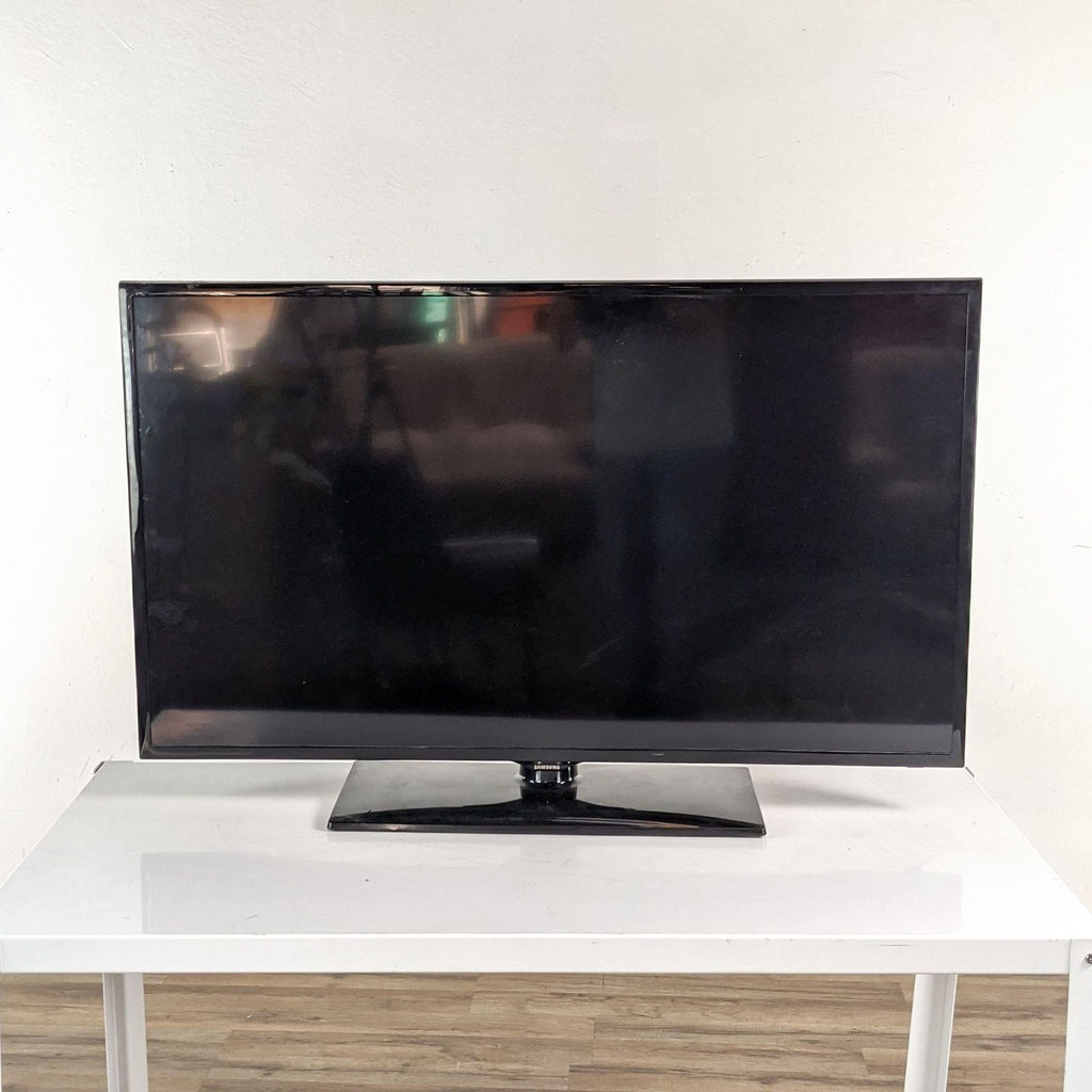 Samsung TV on a white table, wooden floor background.