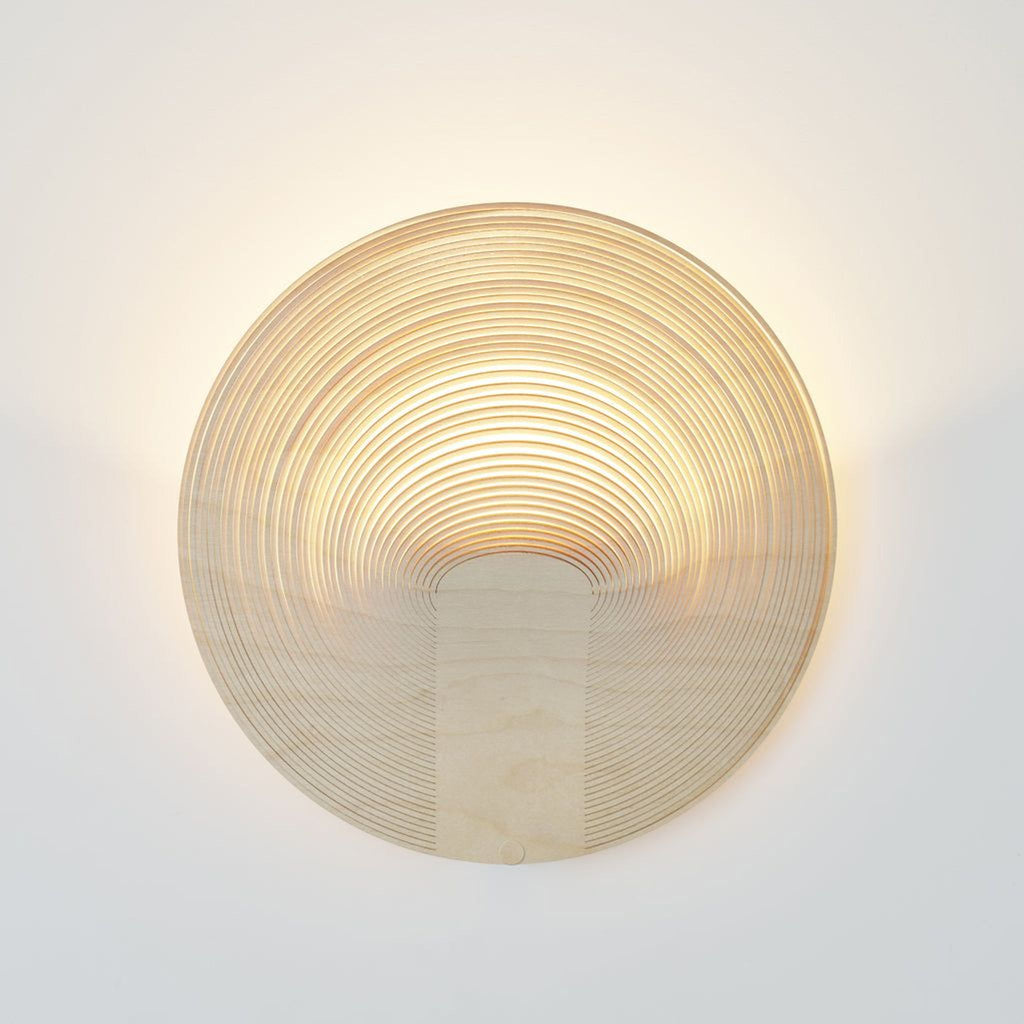 3. Illuminated Reperch wall lamp showcasing layered wood rings that create a warm, glowing effect.