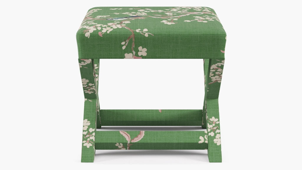 a green and white stool with a floral pattern and a bird on it.