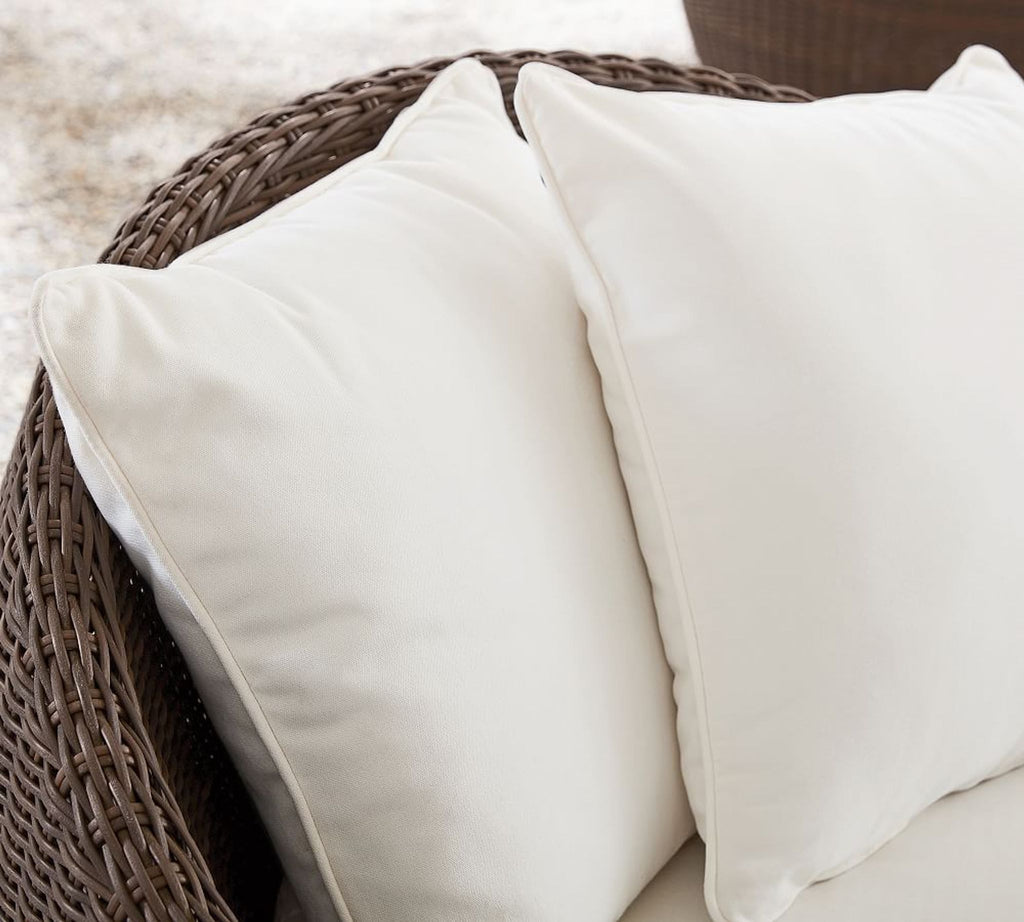 3. Detail view of two soft, white pillows resting inside a circular wicker papasan chair, perfect for relaxing.