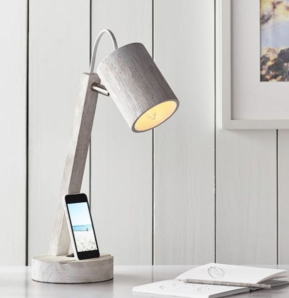 Pottery Barn Teen wood task lamp on a desk next to a phone and notebook, illuminated.