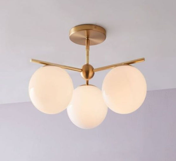 Antique brass finish ceiling light with three milk-colored glass globes by West Elm.
