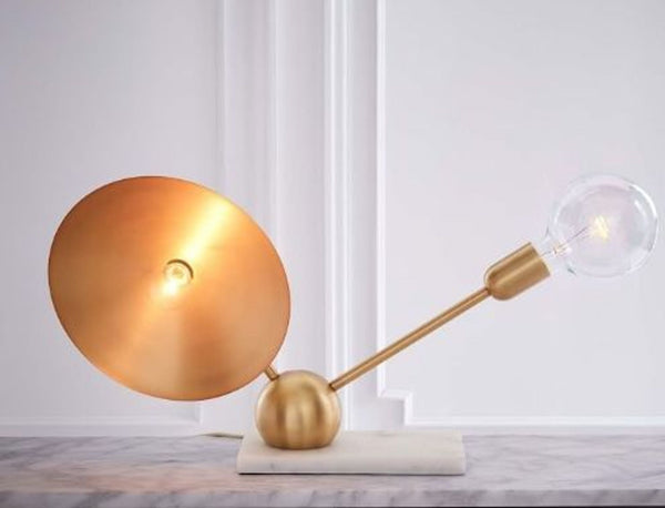 1. "West Elm antique brass table lamp by Rosie Li Studio, with a glowing orb-shaped shade and an exposed bulb on marble base."