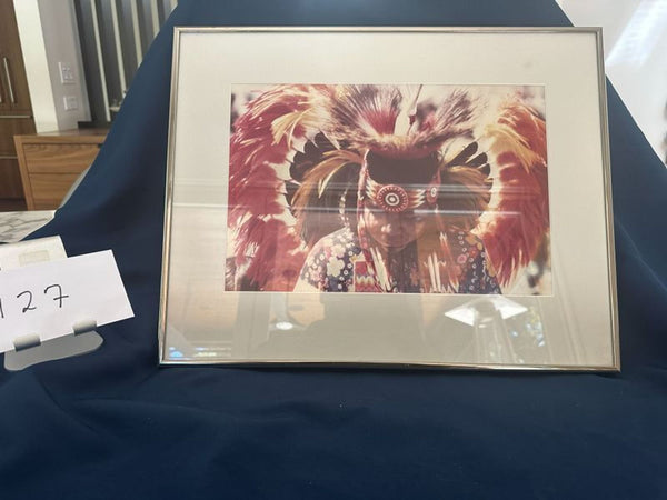 1. Framed print of person in feathered headdress, with a card labeled "127" beside it, displayed on blue cloth.