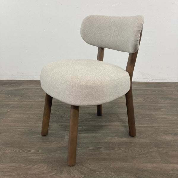 Alt text 1: The Jane dining chair by Reperch with an elegantly curved back and sculptural wooden legs, upholstered in a textured light fabric.