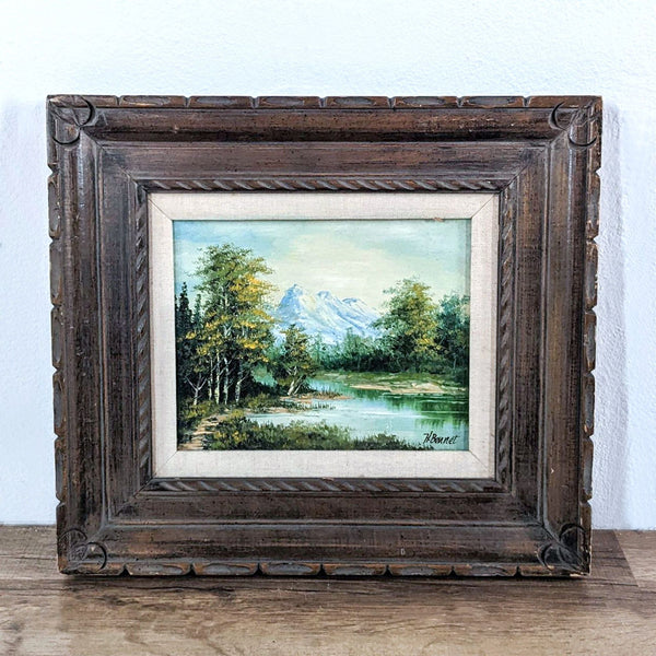 1. H. Bennet painting in Reperch frame depicting a serene mountain landscape with trees and a lake, placed on a surface against a wall.