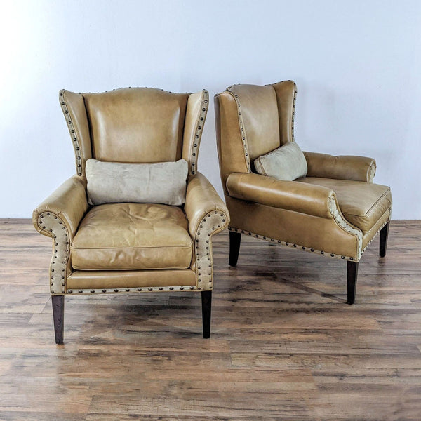 Pair of tan Barclay Butera Lifestyle leather wingback chairs with nailhead trim, shown from the front.