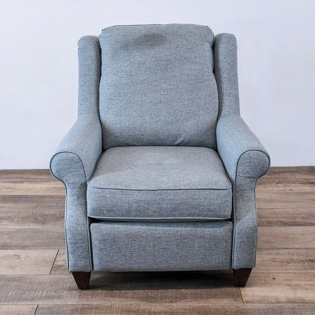 A grey Bassett Furniture power recliner with plush cushioning against a white wall on wooden flooring.