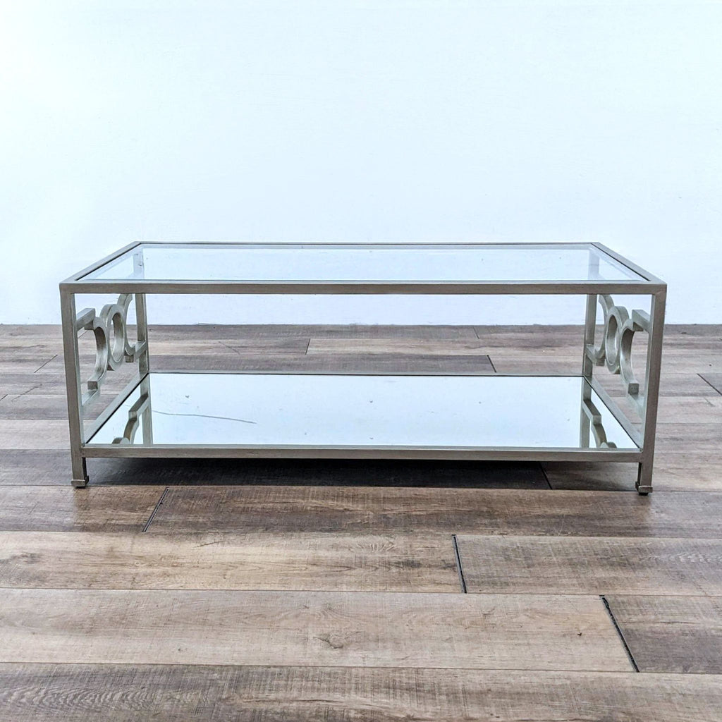 Neiman Marcus coffee table with a sleek metal base and mirrored top and shelf, on a wooden floor.