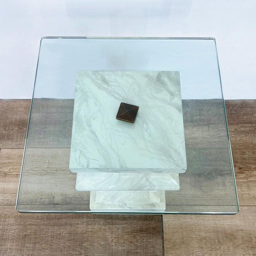 Top view of a square Reperch marble end table with clear glass top and a small object placed at the center.