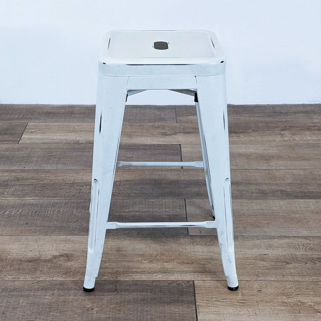 Reperch brand distressed white stool, featuring a square top and sturdy metal legs, placed on a hardwood surface.