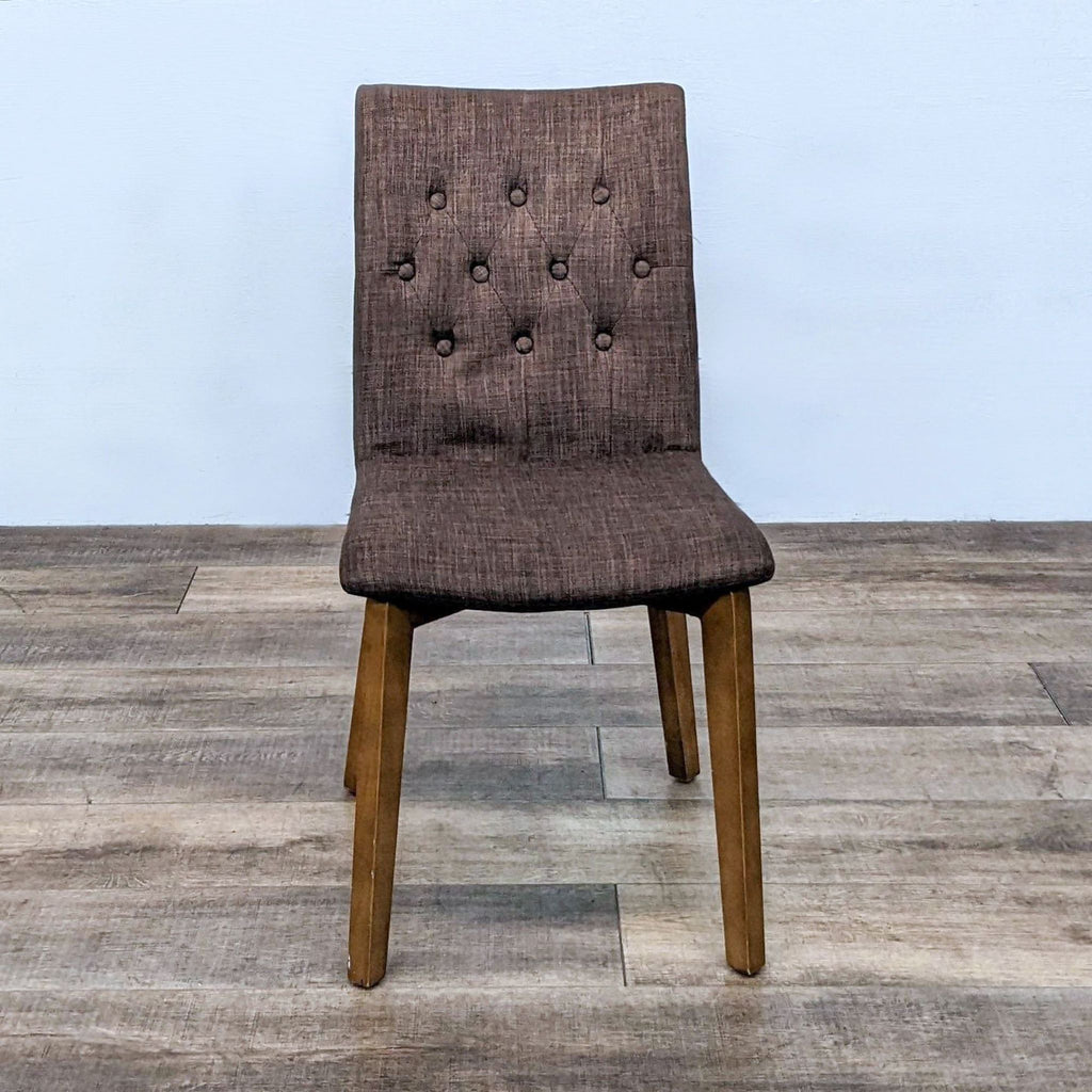 Zuo Modern Orebro dining chair with button-tufted upholstery and wooden frame on a wooden floor.